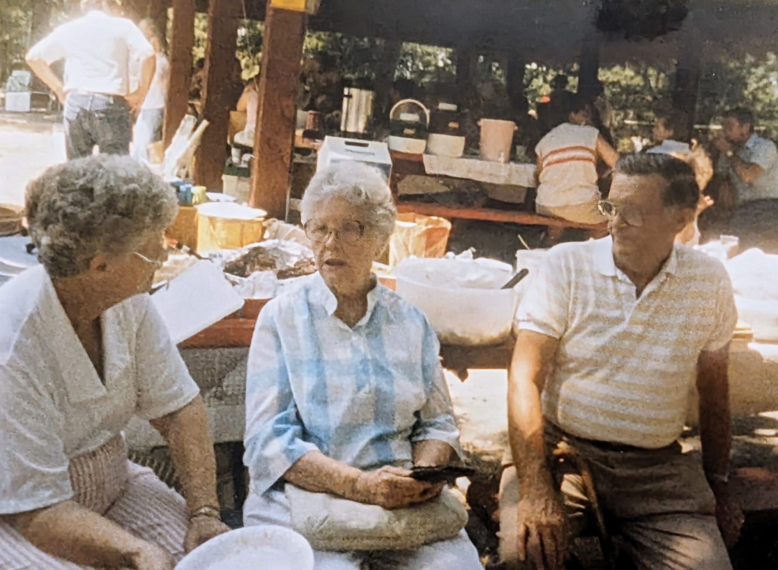 Elderly caucasian woman talking with a middle aged couple at a group gathering outdoors