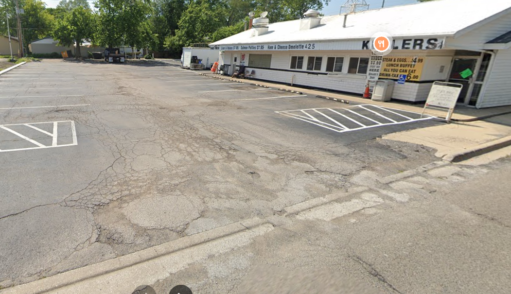 parking lot next to an old restaurant painted white with a the name Kellers painted on it
