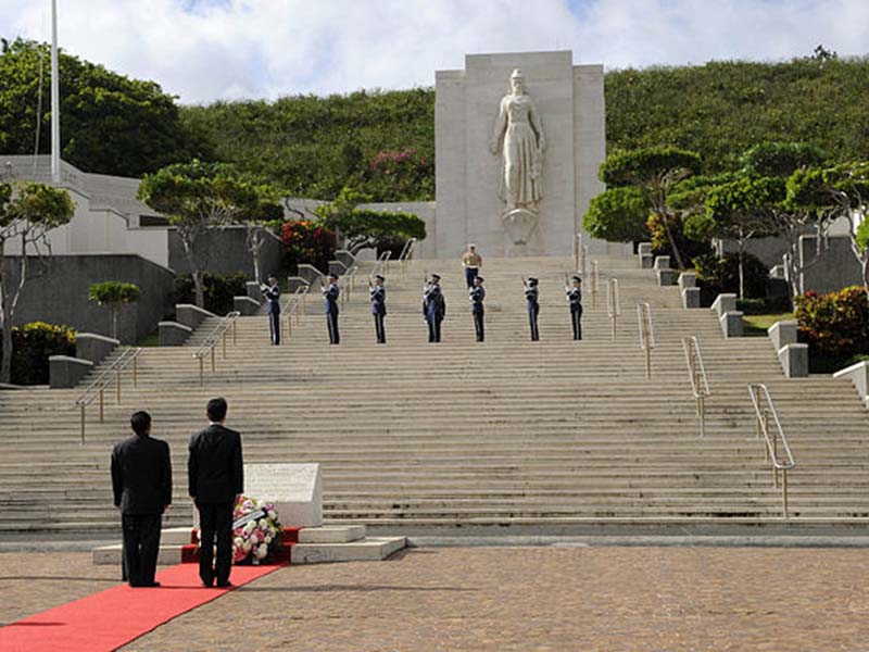 soldiers face large stone memorial 
