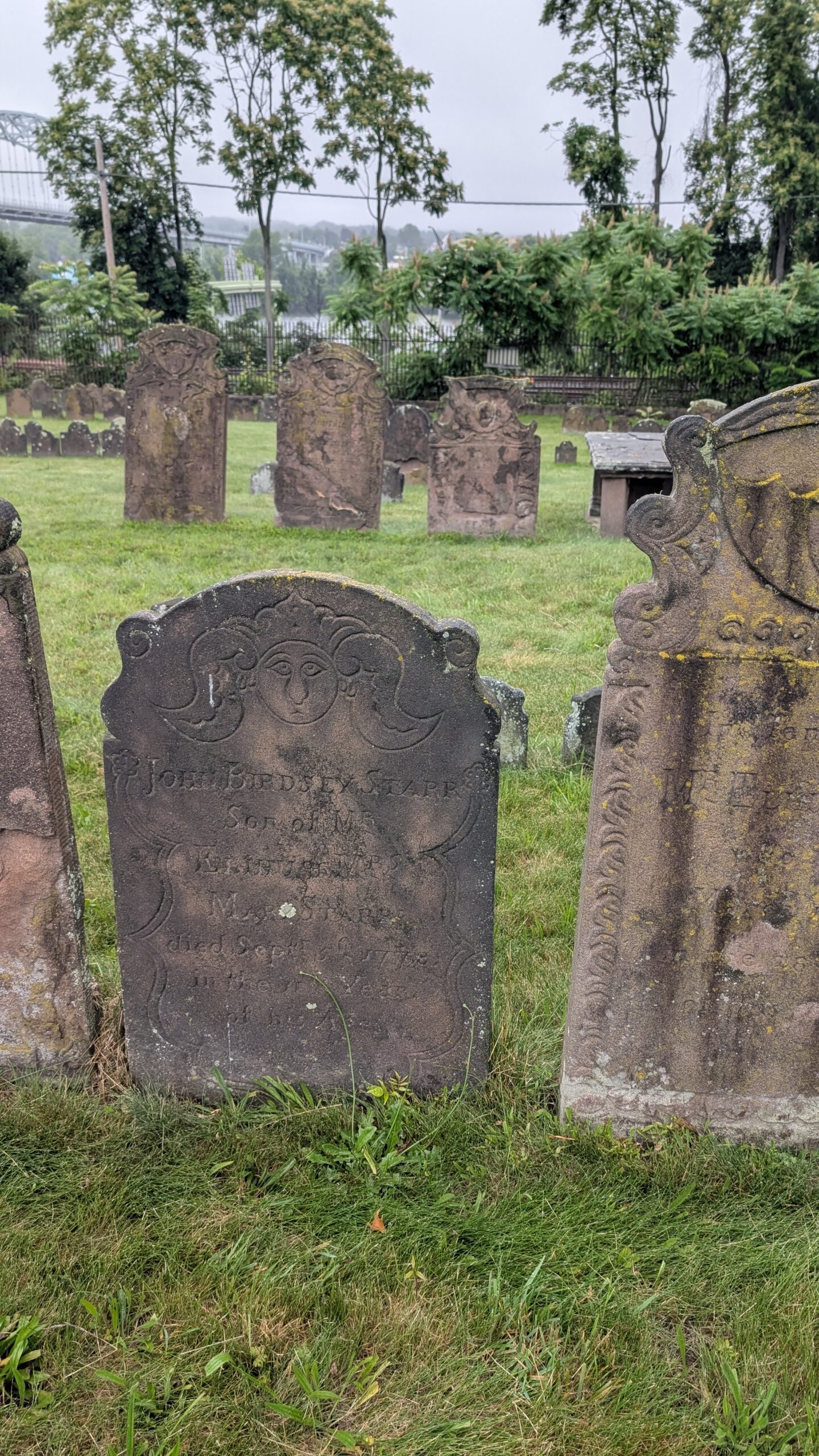 ornate brownstone grave marker with a face and scroll work says John Birdseye Starr Son of Mr. Elihu and Mrs Mary Starr died Sept 1778