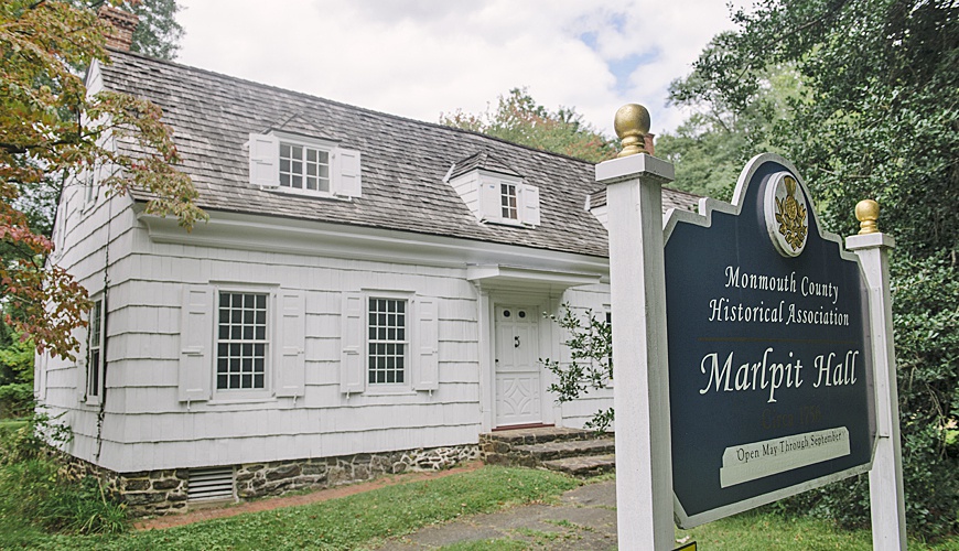 wooden white house with prominent sign in the front yard