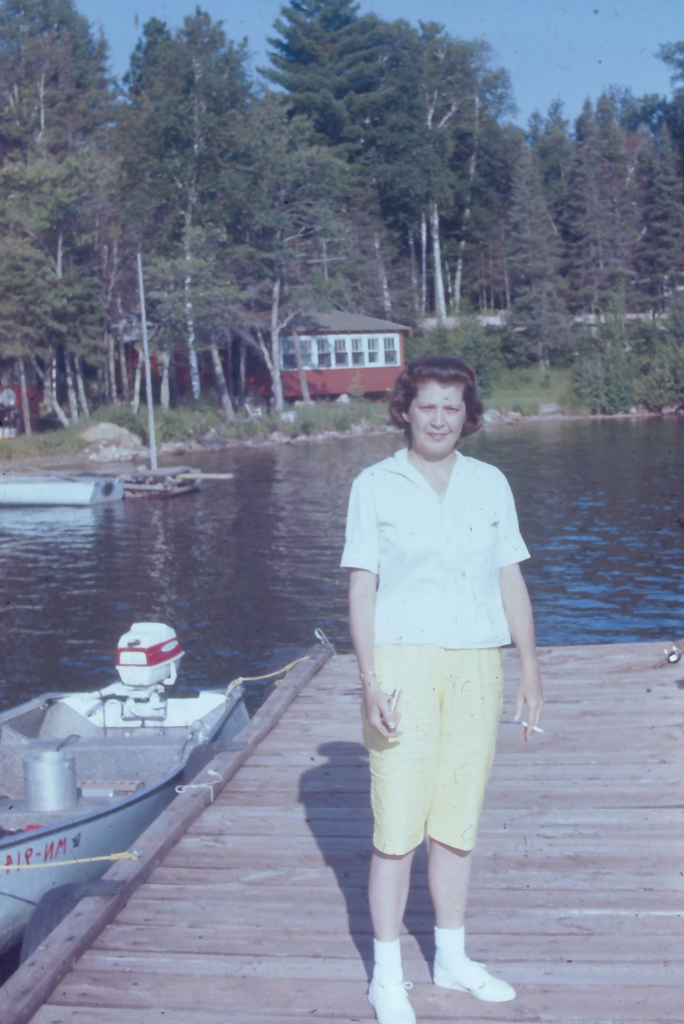 woman on dock of a small lake cigarette in hand